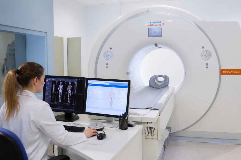 Operatorka przy monitorach obsługuje aparat rezonansu magnetycznego Siemens w pracowni diagnostycznej