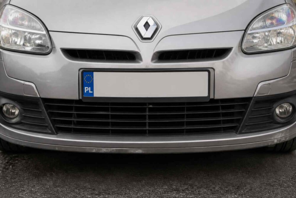 Przedni zderzak Renault Megane z tablicą rejestracyjną Zbliżenie srebrnego Renault Megane z grillem, reflektorami przeciwmgielnymi i zamazaną tablicą rejestracyjną