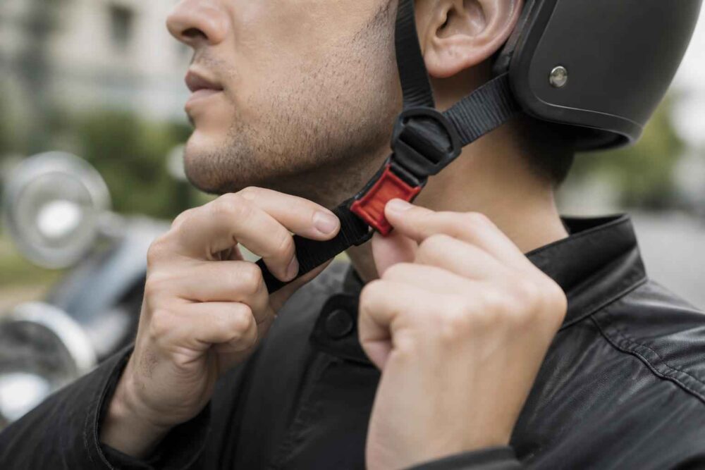 Mężczyzna zapina pasek czarnego kasku motocyklowego pod brodą